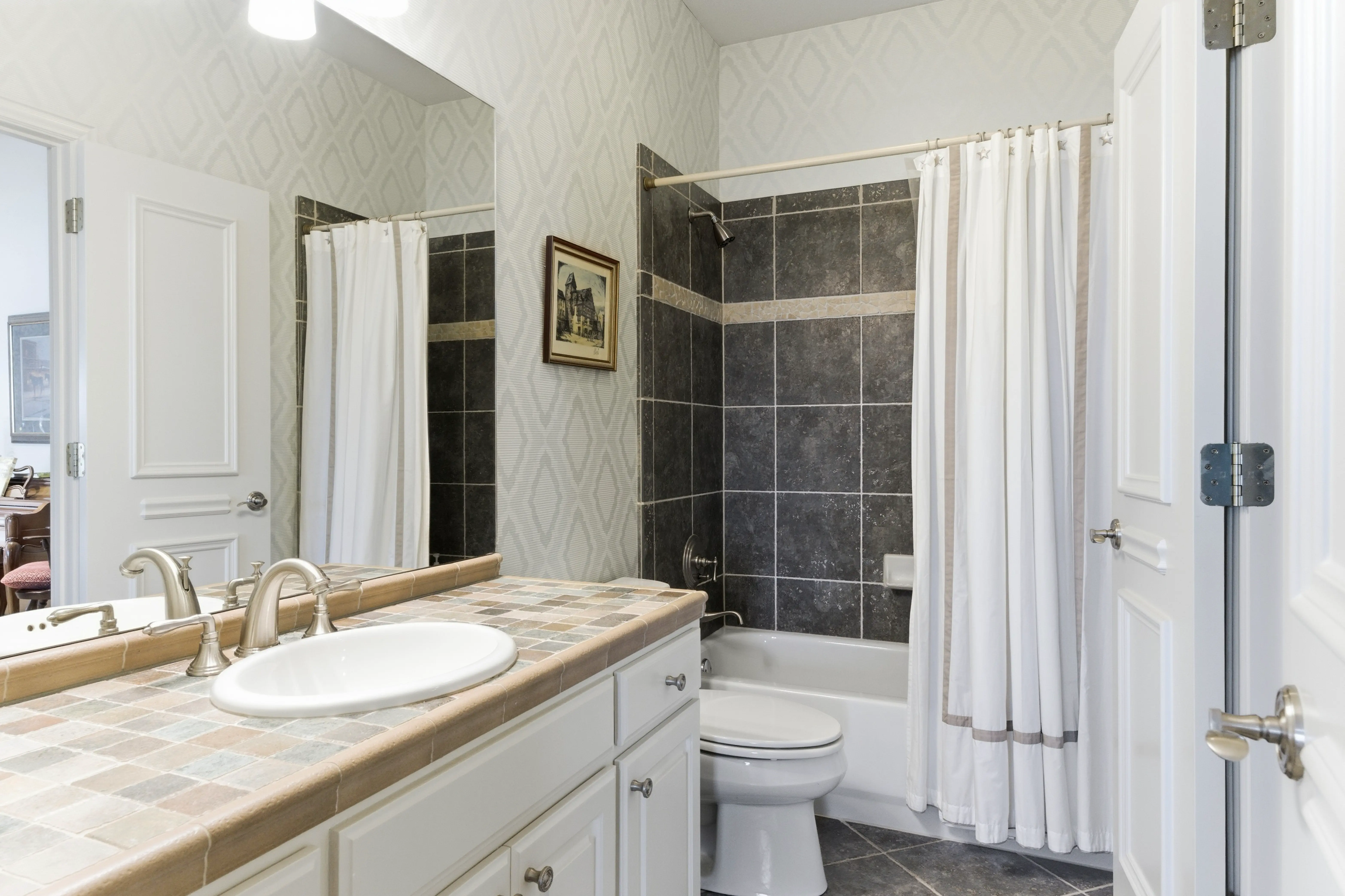 Guest bathroom with diamond wallpaper, tile shower-tub combo, and single vanity